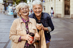 Zwei lachende Seniorinnen in einer Fußgängerzone